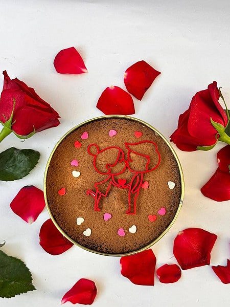 Heart-decorated chocolate cake tin surrounded by roses